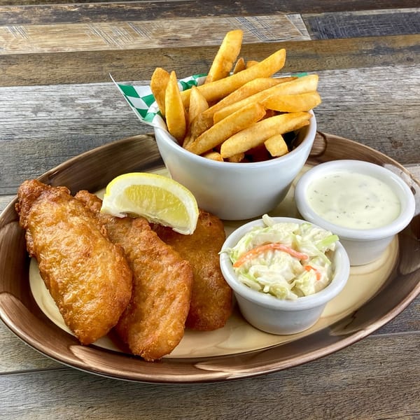 Lucky's Restaurant & Bar fish and chips with coleslaw, tartar sauce, and a lemon wedge.